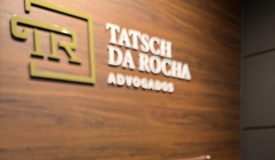 Logo de latão da Tatsch da Rocha Advogados na parede de madeira da recepção