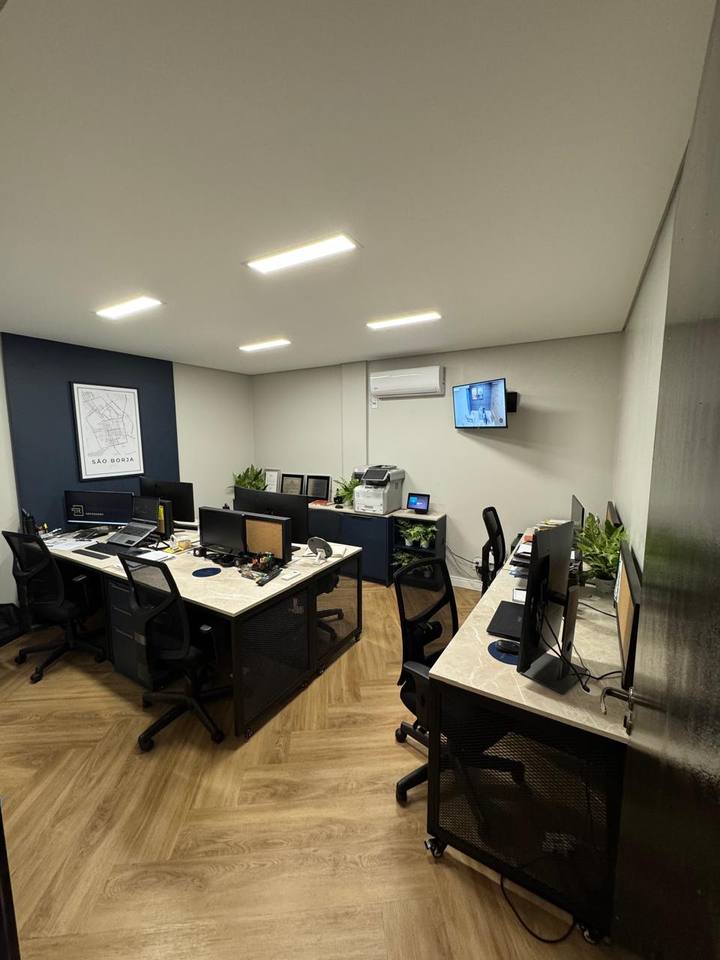 Área de trabalho do escritório, com as mesas da equipe e o quadro de São Borja na parede